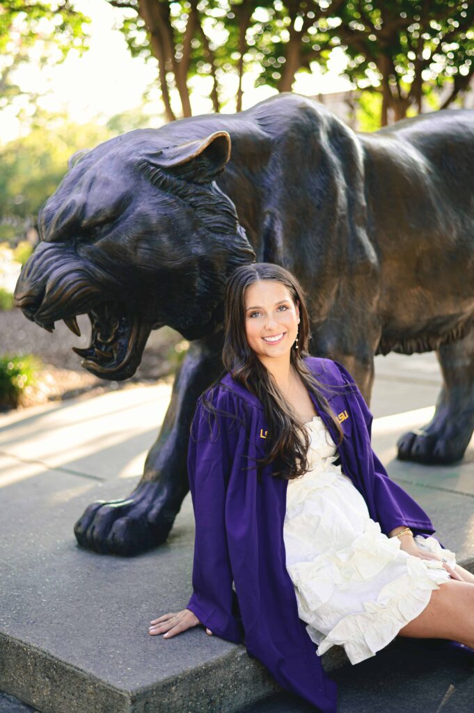 LSU senior poses at the Mike the Tiger Statue during graduation portraits on LSU campus in Baton Rouge, Louisiana