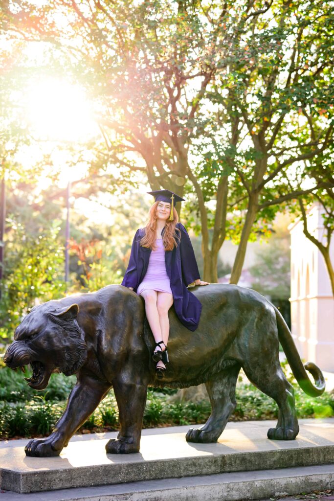 LSU senior poses at the Mike the Tiger Statue during graduation portraits on LSU campus in Baton Rouge, Louisiana